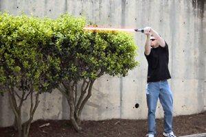 Lightsaber trimming a hedge.
